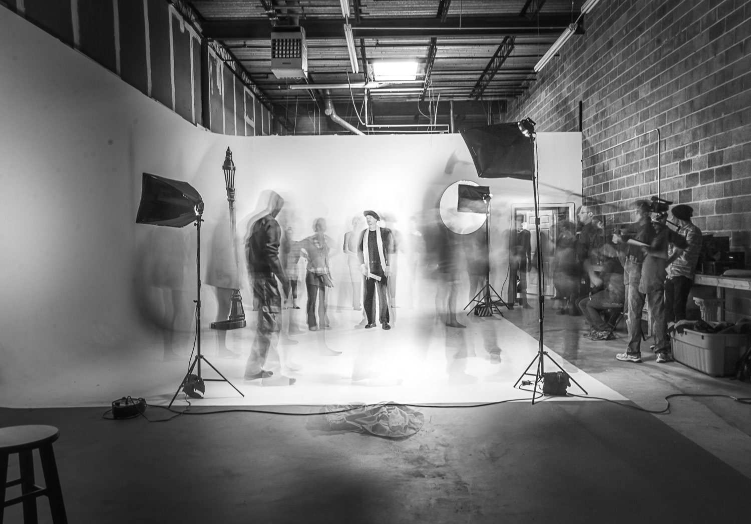 Long exposure of a film set: one actor stands sharp in the center while everyone in motion blurs into ghosts